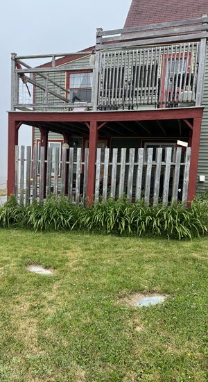 Wooden deck and railing on two-storey house with surrounding greenery